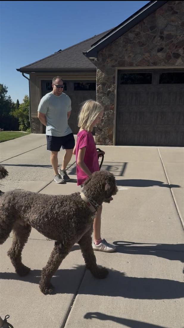 Dog walking closely beside its owners on a leash